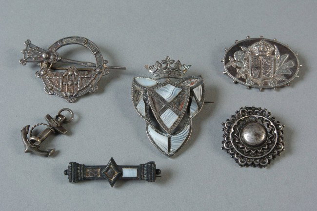 LOT OF BRITISH STERLING SILVER BROOCHES: Includes an oval brooch with union crest, Birmingham anchor; a J.M. Co. marked brooch like a cloak pin, a multi-piece brooch with applied stones, an anchor brooch with inset stones and missing pin; an