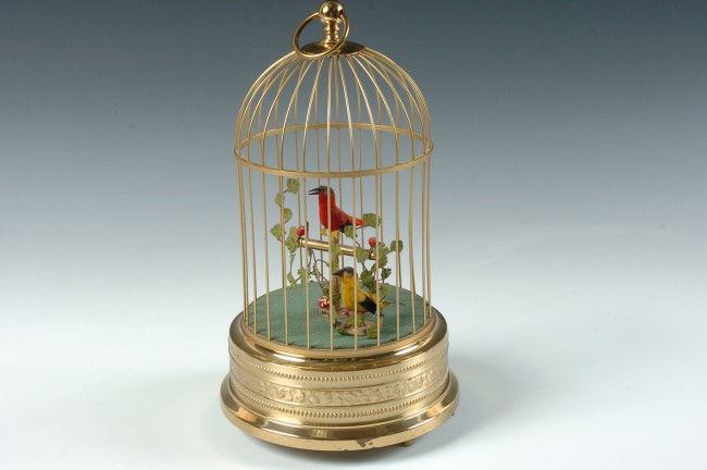 A SINGING BIRD AUTOMATON MUSIC BOX: Winding and functional singing bird automaton and cage, marked 'Germany' . Measures 11.5 x 6.5 inches.
