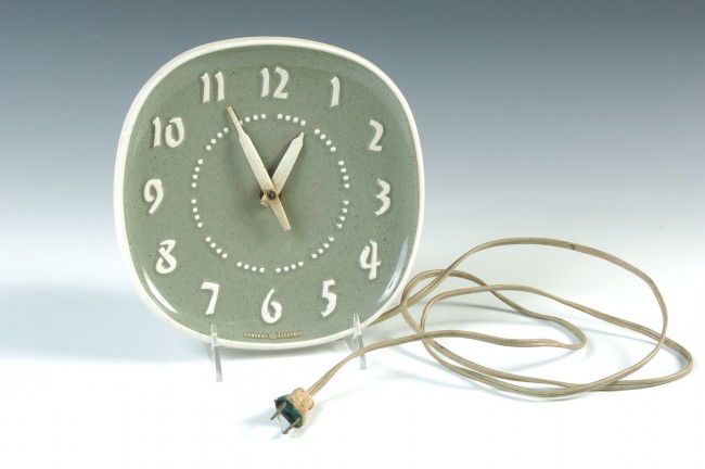 A RUSSEL WRIGHT WALL CLOCK: Green with raised white letters, white plastic movement housing. With cord and plug.