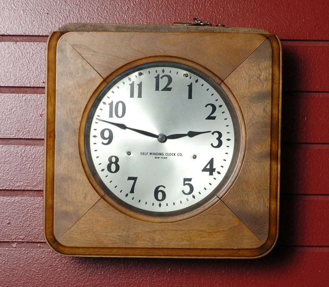 A SELF-WINDING CLOCK CO. GALLERY CLOCK: Nicely preserved paper instructions inside case. Battery powered. Key lock door, with key. 13 x 13 inches overall.