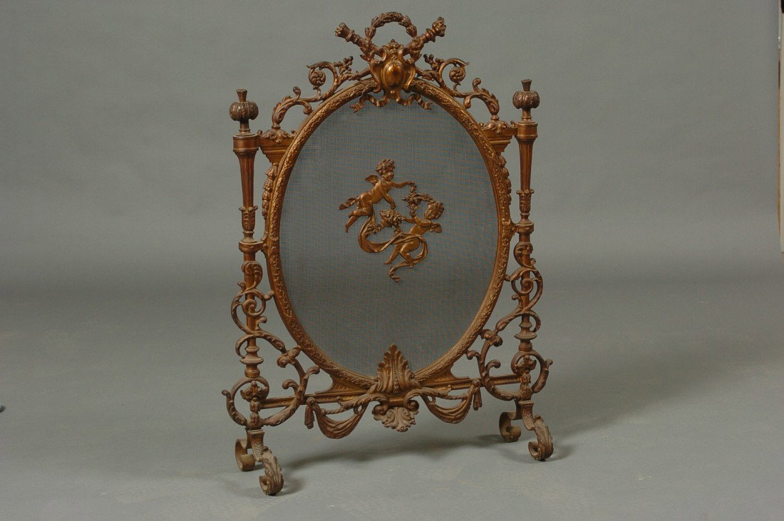 LOUIS XV-STYLE BRONZE DORE FIREPLACE SCREEN: Oval form frame molded with laurel and berries, top central motif of cabochon, laurel and ribbon, bottom with acanthus leaf; surrounded with scrolling acanthus and rosettes, flanked by supports surmou