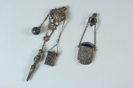 TWO ANTIQUE SILVER CHATELAINE PIECES: Including an .800 silver Chatelaine with accoutrements that include a chased and pierced vinaigrette marked sterling that measures 1 inch in diameter, plus a cherub-faced vinaigrette scent bottle mark