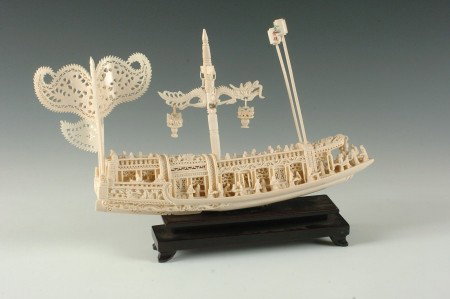 FINELY CARVED CHINESE IVORY JUNK SHIP MODEL: Elaborately carved ivory junk with two detachable posts, a central mast with hangers, and four flags. Beautiful details, with two lamps hanging forward, a couple dozen people scattered throughout, and