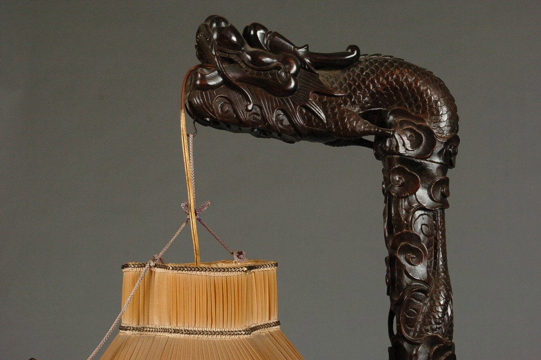 19TH C. CARVED ROSEWOOD CHINESE DRAGON FIGURAL LAMP: The base with carved designs of bats and three openwork buttresses that join the rising central shaft with winding scaly body that ends with the dragon figural support for the pleated silk pagoda shap