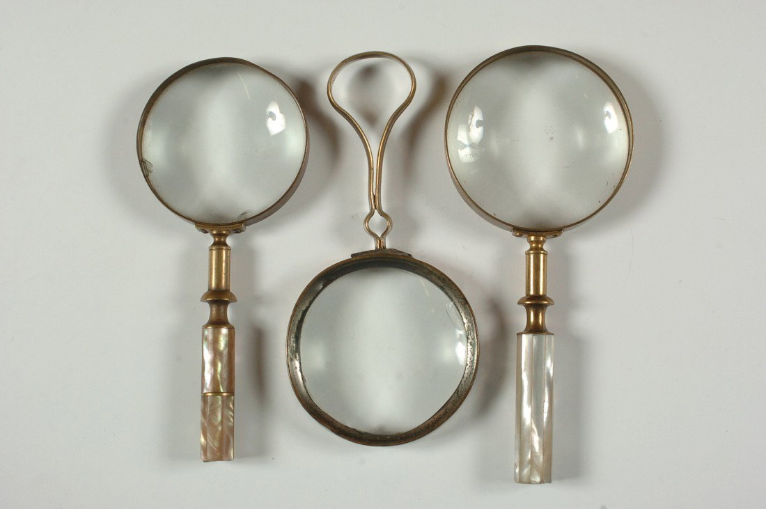 THREE VICTORIAN MAGNIFYING GLASSES: One nickel plated brass handle and frame, 7 x 3.25 inches; and two mother-of-pearl handled pieces, 7.75 x 3.25 inches and 7 x 3 inches.