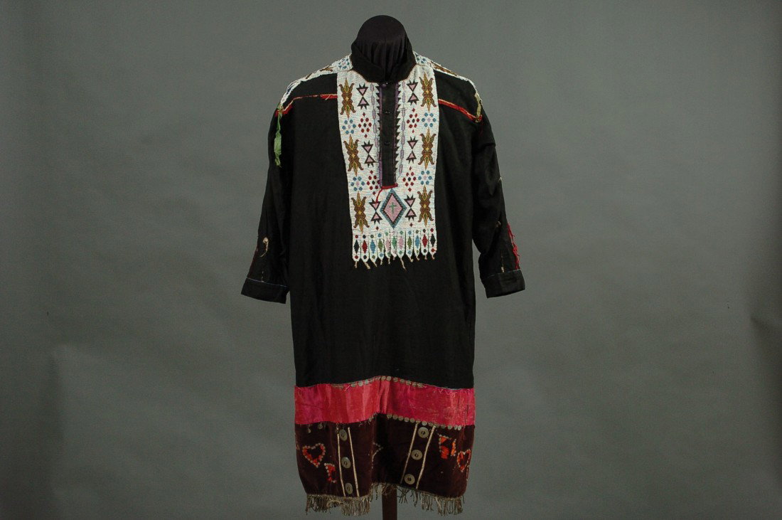 A PLAINS BEADED DRESS: Black cloth with panels of white beadwork interspersed with various geometric designs, measures 38 inches hem to collar, 20 inches shoulder to shoulder.
