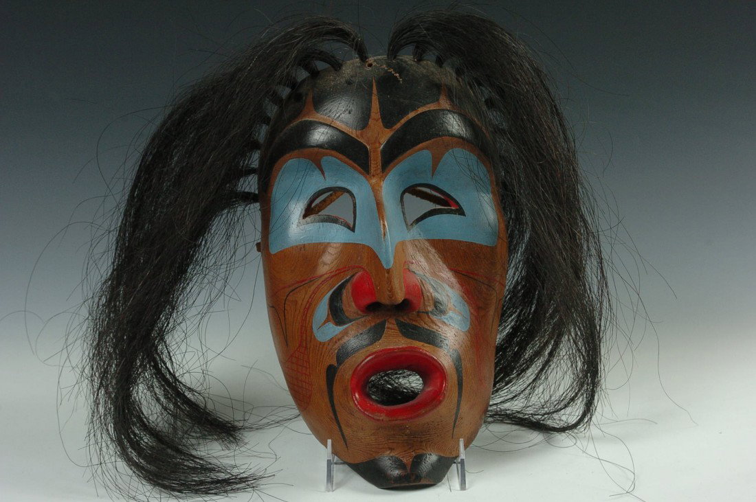 A KWAKIUTL 'WIND' MASK BY TOM JOHNSON, FORT RUPERT BC: A carved and painted wood mask with horse tail strands, the image also known as DZUNUKWA or similar to 'Wild Woman of the Woods', measures 12 x 7 inches. Purchased American Indian Treasures, 1981