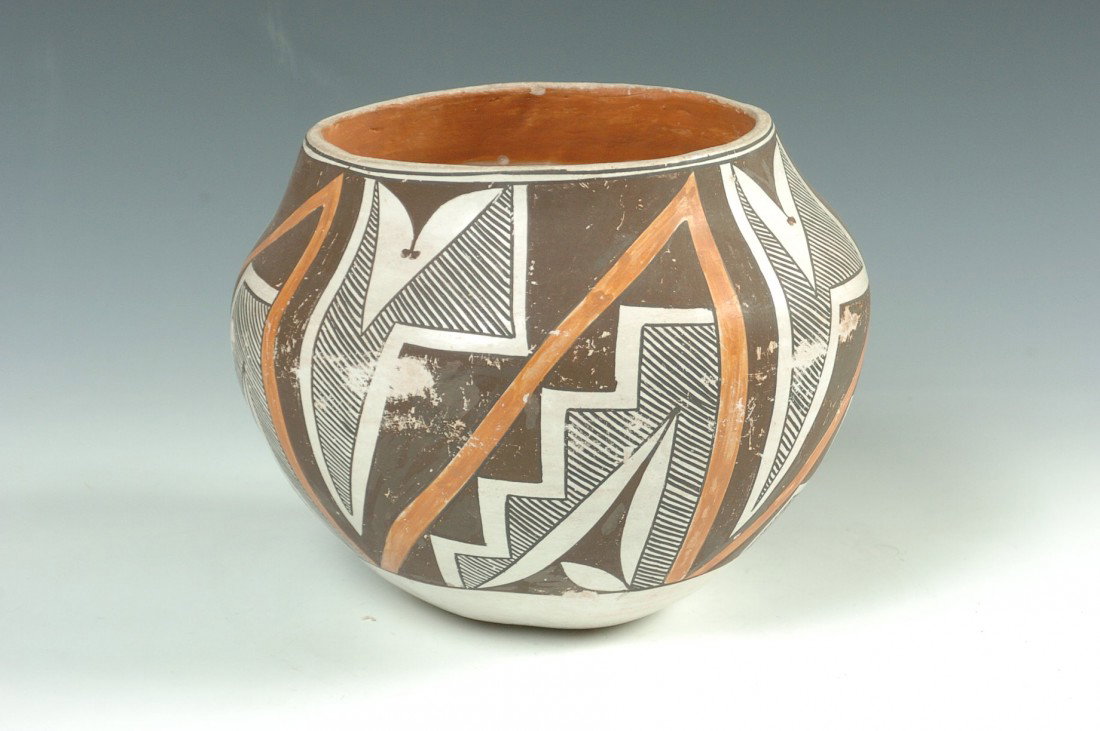 AN ACOMA POTTERY OLLA: Decorated with Kiwa steps, feathers and geometrics in orange, black and red, measures 6.5 x 7 inches.