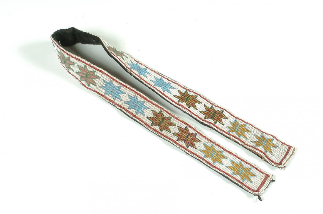 A WINNEBAGO LOOM BEADED BELT: A design of sixteen 8-pointed stars in pairs with a central design, measures 34.75 x 2 inches.