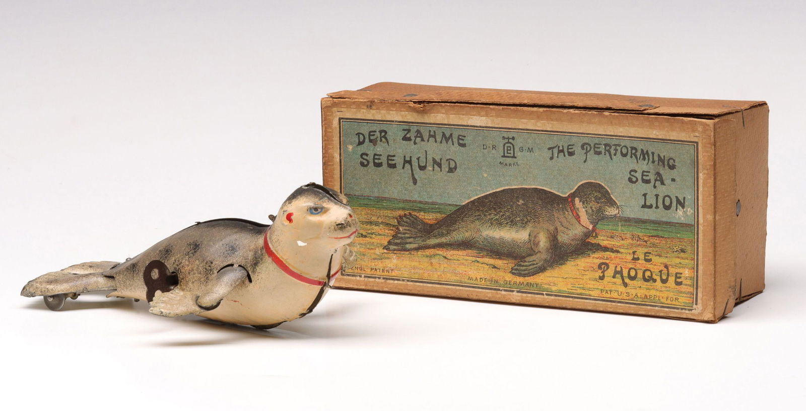 A LEHMANN PERFORMING SEA LION TIN WIND-UP IN BOX: The lithographed tin wind-up toy made in Germany circa 1900 is accompanied by the original box. Measures 2.75 x 7.25 x 4.5 inches. Without proof of exemption,, be aware that internet sales tax applies