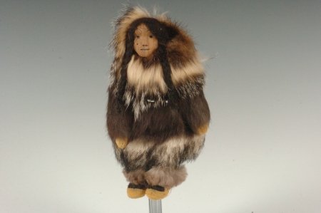 INUPIAQ DOLL SIGNED IVA LISBOURNE: An Inupiaq doll by Iva Lisbourne of Wainwright, AK with a carved wooden face and inlaid teeth, dressed in furs and sueded leather, signed in pen under the doll's coat, 8 inches.