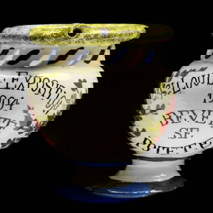 A 1904 ST. LOUIS WORLD'S FAIR SOUVENIR PUZZLE MUG: The Italian faience puzzle mug states 'St. Louis Exposition 1904 Bevete Se Potete (Drink If You Can),' signed with a maker's mark on the base. Measures 5 x 6.25 x 4 inches. Without proof of exemption,