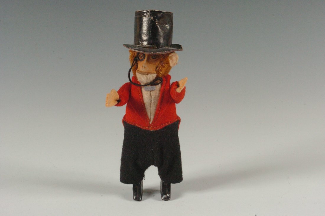 SCHUCO MONKEY IN TOP HAT: Schuco wind-up Monkey in top hat wearing a monocle, red coat black pants and a top hat. Measures 6 x 2 inches.