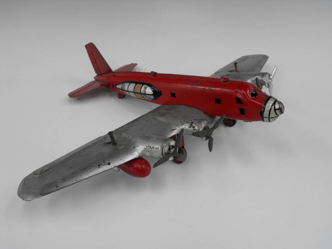 MARX PRESSED STEEL BOMBER AIRPLANE: Pressed steal airplane bomber made by Marx, red & silver, push on wing buttons and bombs drops. Measures 2.75 x 10 inches with a 14.5 inch wing span.