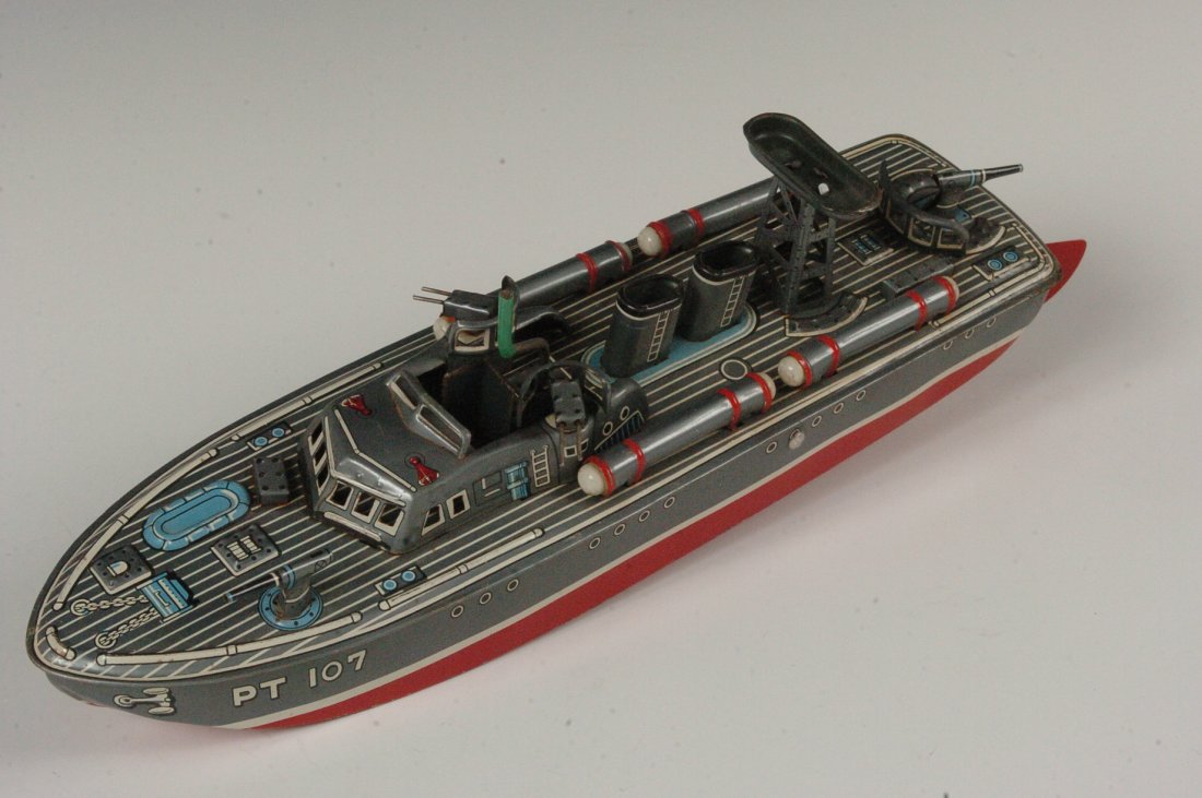 PT 107 CRANK OPERATED TIN TOY TORPEDO BOAT: PT 107 crank operated Torpedo Boat, made by K toys in Japan, ( same as the Linemar toy). Measurements 3 x12 inches including rudder.