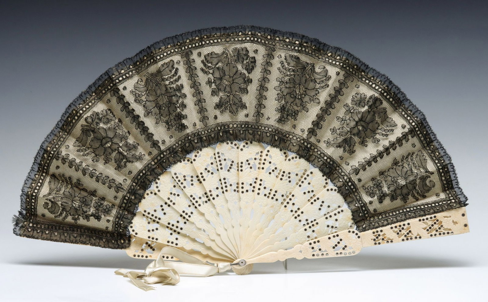 ELABORATE 19TH C HAND FAN W/ BLACK LACE & SILVER INLAY: The carved bone sticks with inlaid silver spots are overlaid with hand made black lace panel on the pleated leaf. Measures 11.5 x 19.75 inches. Without proof of exemption, be aware that internet sales