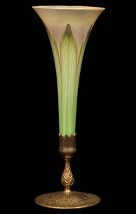 A TIFFANY FAVRILE TRUMPET VASE WITH FEATHERS IN BRONZE: Early 20th Century. The favrile art glass trumpet vase decorated in a fired-on iridescent finish of pulled feather decoration of green and gold is fitted to a dore' bronze nozzle of elongated upward r