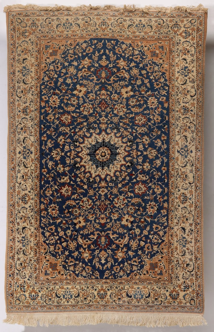 A PERSIAN NAIN RUG CIRCA SECOND QUARTER OF THE 20TH C.: The pile weaving with silk highlights is centered by an ivory multi-pointed central medallion on blue field covered in meandering vines issuing palmettes, flower heads and leaves bracketed by tan span