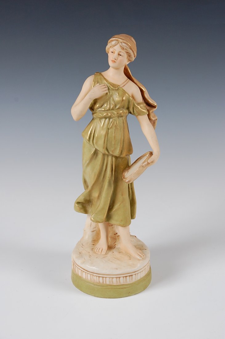 ROYAL DUX FIGURE OF WOMAN WITH TAMBOURINE: Figure of a man carrying a dead swan, base with decorative border. Base with Royal Dux triangle seal, incised 2075 and 9, and 37. Stands 13 inches.