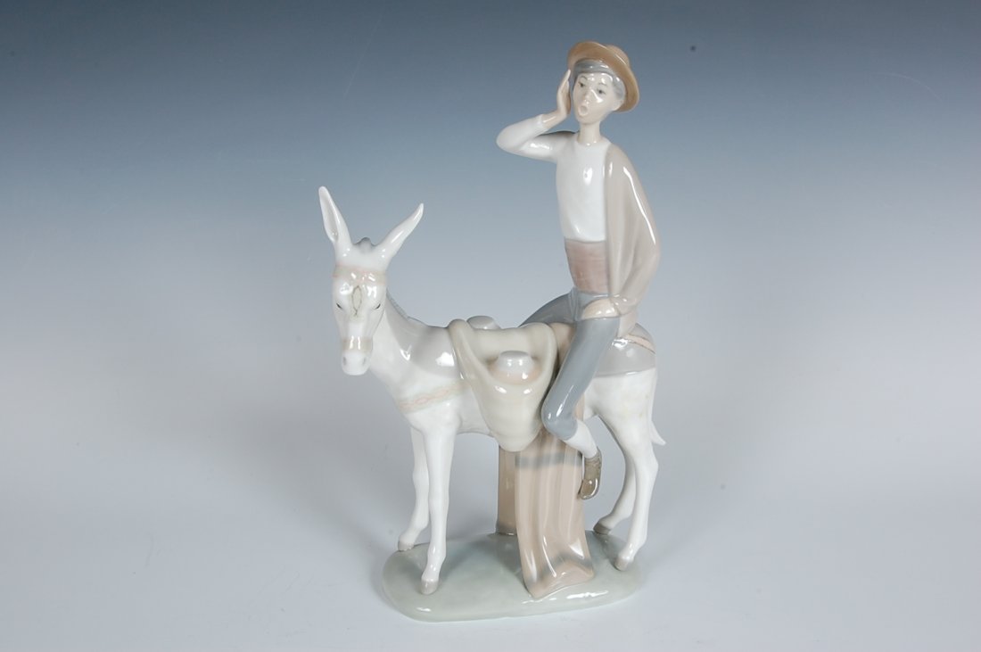 LLADRO PORCELAIN FIGURE OF BOY ON A DONKEY: Figure of a boy calling out from the back of a mule, stands 11.25 x 6.75 inches, Lladro marked base.