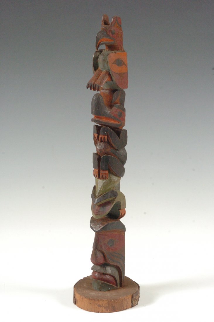 A GOOD ESKIMO INDIAN CARVED TOTEM CIRCA 1925: A nice carved and painted wood totem pole with log slice base and paper label on the reverse that reads, ' Ye old curiosity shop, Colman Dock, Seattle', measures 13.5 inches.