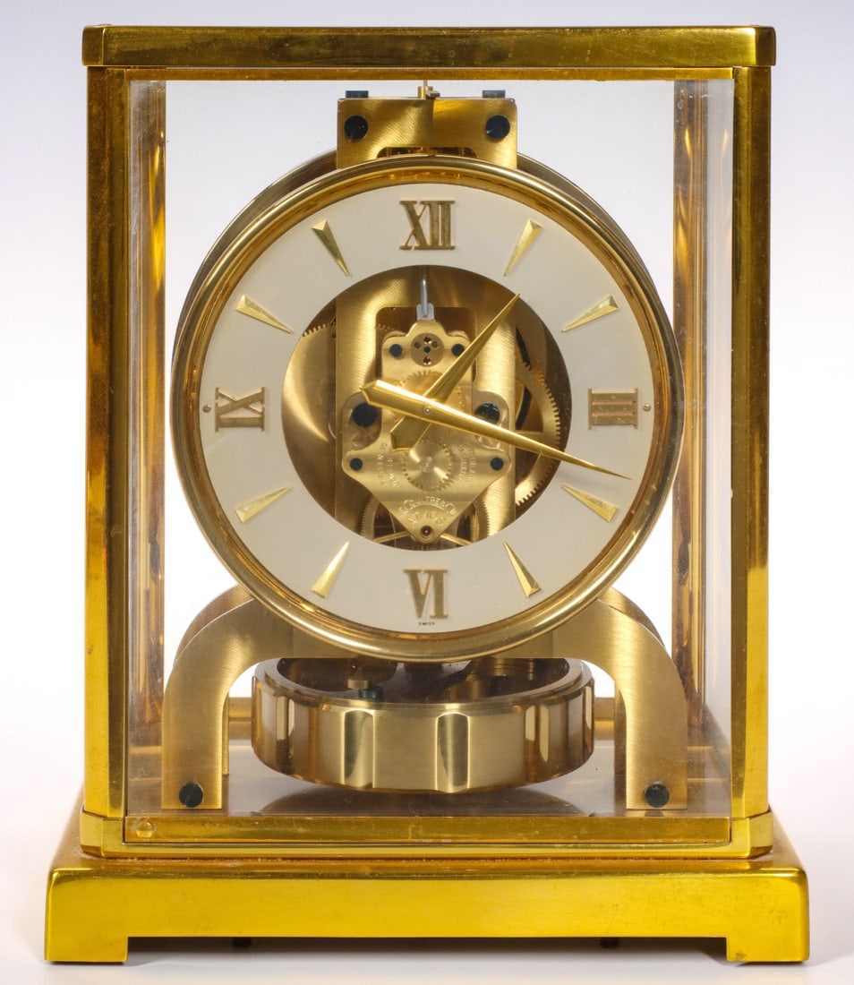 A LeCOULTRE ATMOS CALIBER 526-5 PERPETUAL TIMEPIECE: The Swiss made self-winding timepiece with ivory dial in brass bezel divided by bayonet hour markers and roman numerals is housed in a glass case, serial number 95136 and signed Atmos LeCoultre & Cie 
