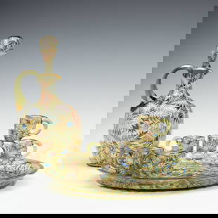 A MOSER GILT AND ENAMEL JUG, TRAY, AND MINIATURE CUPS: Ludwig Moser Late 19th Century The jug and miniature cups are decorated in polychrome enamel fronds and gold trim. A similar green crystal tray very finely decorated in elaborate enamels of a