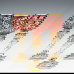 LARGE MOSER GILT AND ENAMEL WINE GOBLETS WITH ACORNS: Each of the three nice, large cranberry bowl goblets is raised on a bulbous blown stem with applied prunts covered in gold. The bowl and stem are both decorated in swirling, colorful enamel oak