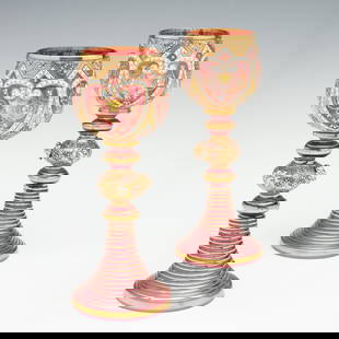 TWO LAVISHLY DECORATED MOSER GOBLETS WITH APPLICATIONS: Ludwig Moser Late 19th Century Each cranberry art glass goblet is decorated in Moser's well-known gilt and polychrome enamel design displaying Islamic influence. The bowl of each is raised on a