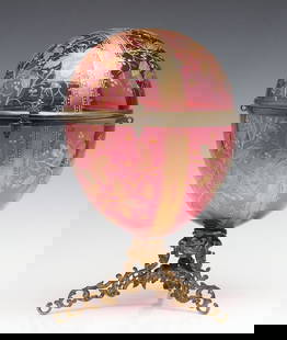 A MOSER GILT AND ENAMELED CRANBERRY GLASS TANTALUS: Late 19th Century The egg form blown glass container is without its interior fittings and exterior ornamental handles. Measures 14 x 8.75 inches. Without proof of exemption, be aware that internet