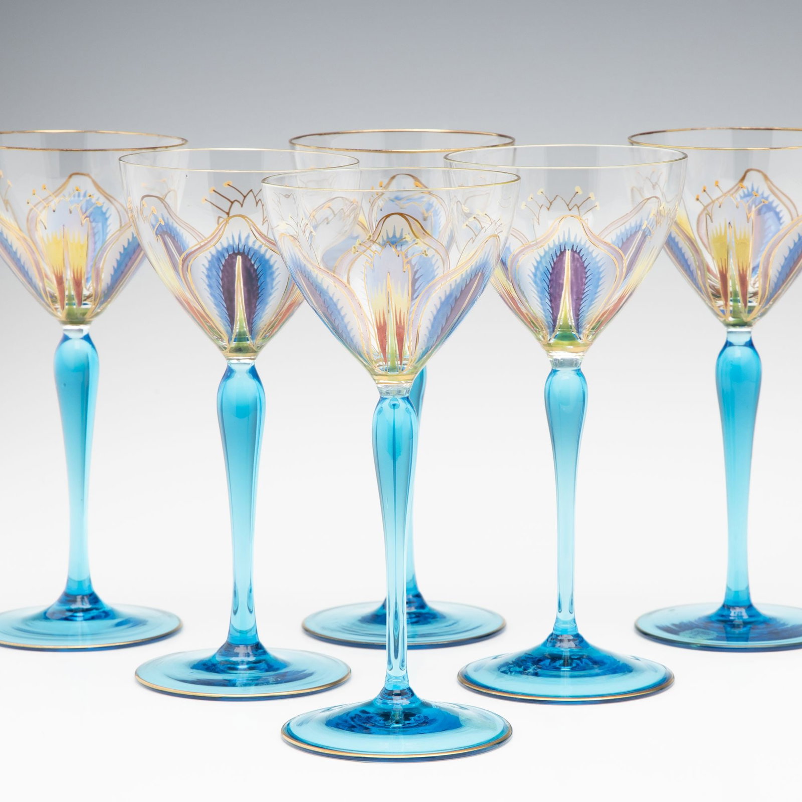 SIX CONTINENTAL ART NOUVEAU INFLUENCE ENAMELED WINES: The wine glasses colorless crystal bowl decorated in fired enamels and raised on a brilliant blue stem are attributed to the German maker Theresienthal. Measure 6.875 inches each. Without proof of exe