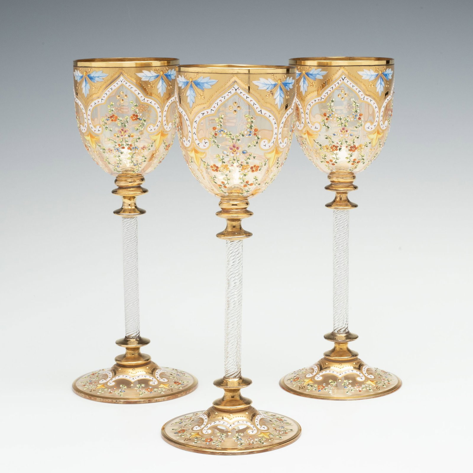 MOSER GILT AND ENAMEL WINES WITH FINE ROPE TWIST STEMS: The fine tall-stem wines display Islamic influence decoration with gold spandrels at the rim embellished with shaded blue enamels and white arabesques enclosing sprays of petite flowers in pleasing co