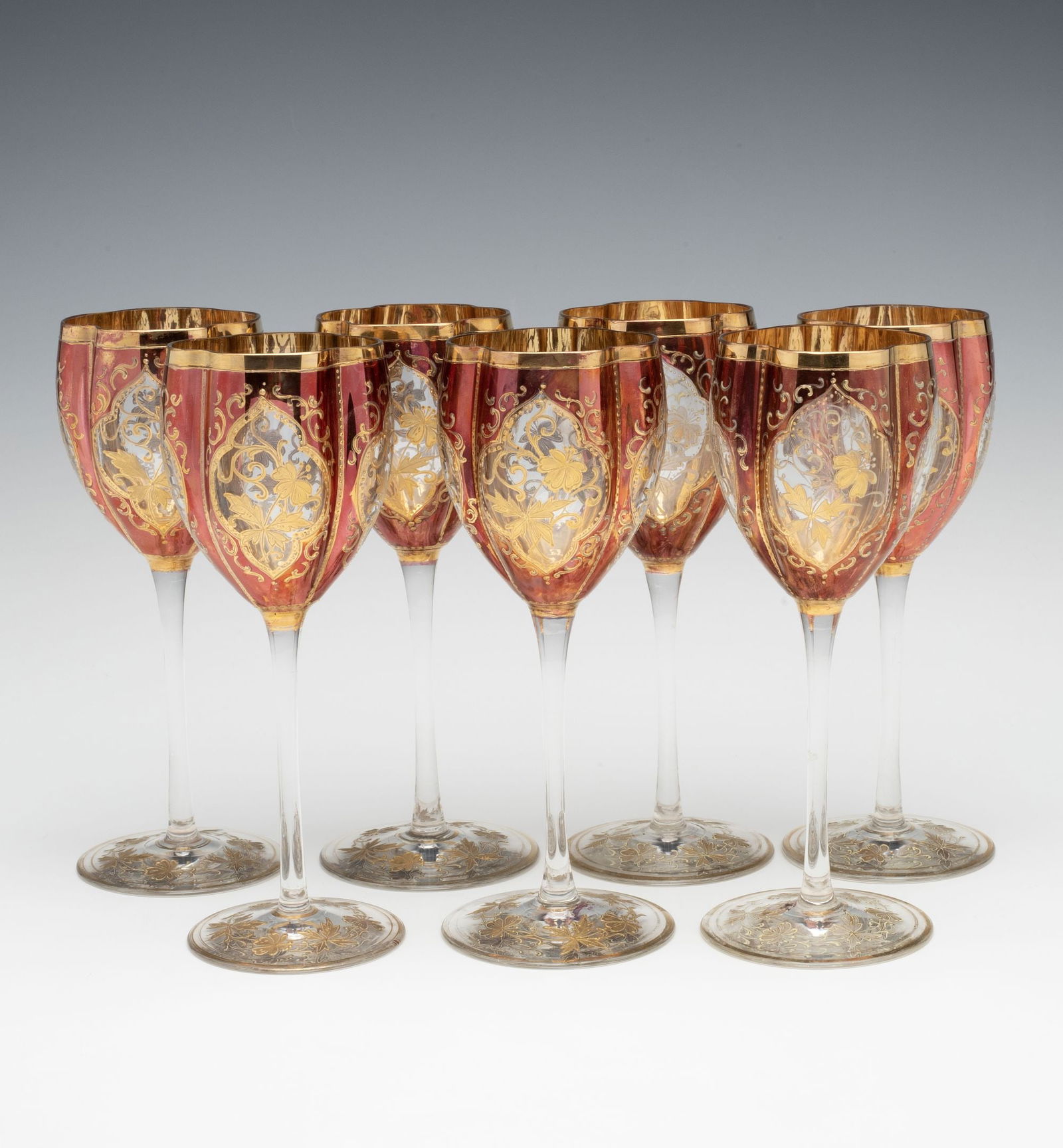 BOHEMIAN FLASHED CRYSTAL ART GLASS WINE GOBLETS: Circa 1900. Each four lobed bowl on slender stem and similarly enameled foot is flashed in a coppery finish with arabesque form windows and enamels in relief trimmed in gold. Each measures 7 x 2.75 in