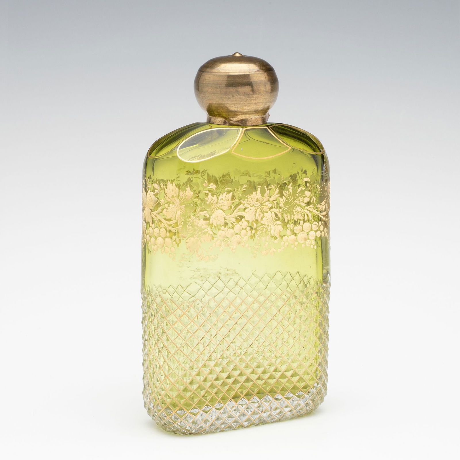 A MOSER QUALITY CUT, CASED AND GILDED GLASS FLASK: Ludwig Moser Early 20th Century The 19th century Moser quality Bohemian art glass flask cased green to clear is cut with large bevels at the shoulder above a band of intaglio cut grapevines gilded and