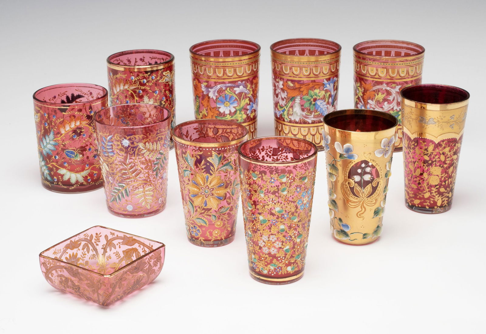 ELEVEN PIECES MOSER GILT AND ENAMELED CRANBERRY GLASS: Ludwig Moser Early 20th Century The collection of nice pieces is offered together as one lot as shown. Sizes range from 1.25 to 4 inches tall. Without proof of exemption, be aware that internet sales