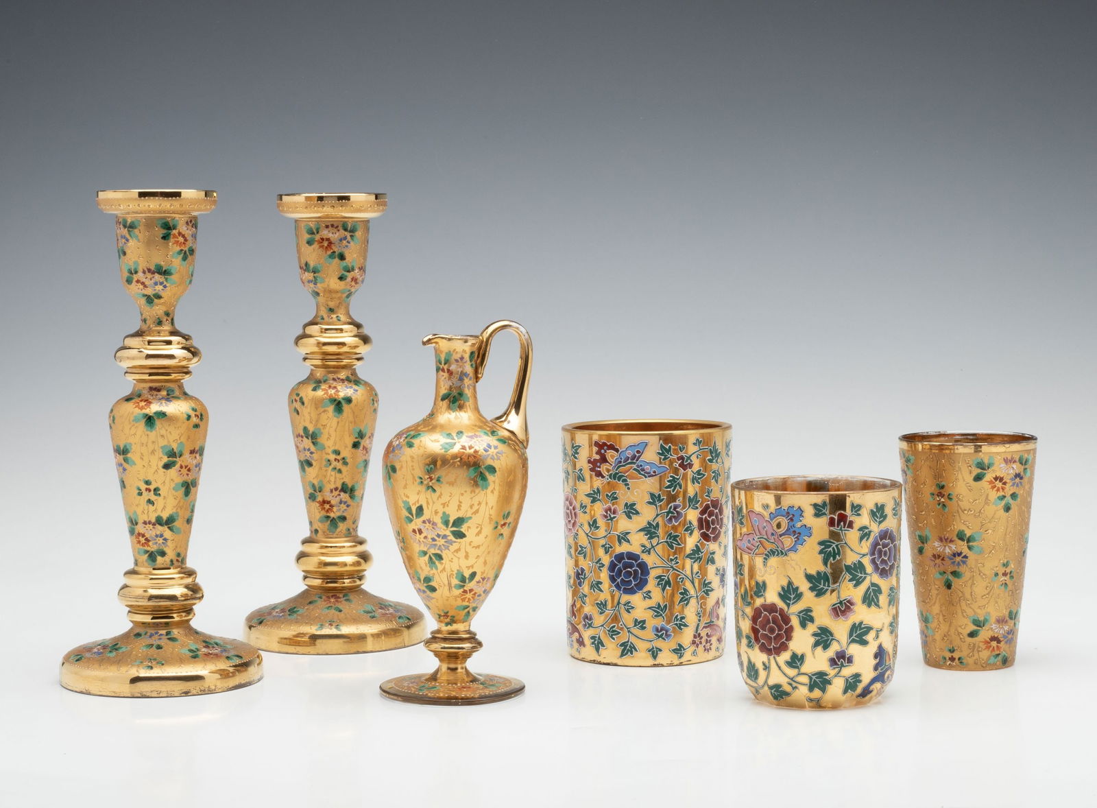 A SELECTION OF 19C. MOSER GILT AND ENAMELED ART GLASS: Ludwig Moser Late 19th Century The collection of colorless crystal articles embodies a line of glassware that Ludwig Moser prepared for the World Exhibition in Paris in 1878. The examples here, partic