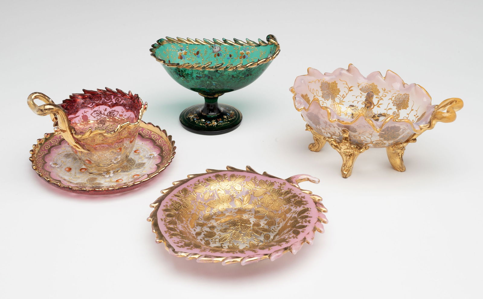 FOUR UNUSUALLY ELABORATE MOSER ART GLASS EXAMPLES: Ludwig Moser Early 20th Century This lot is comprised of very elaborate examples of art glass in the style of Moser. Each has cut and tooled edge work, lavish gilding and elaborate decoration in numer