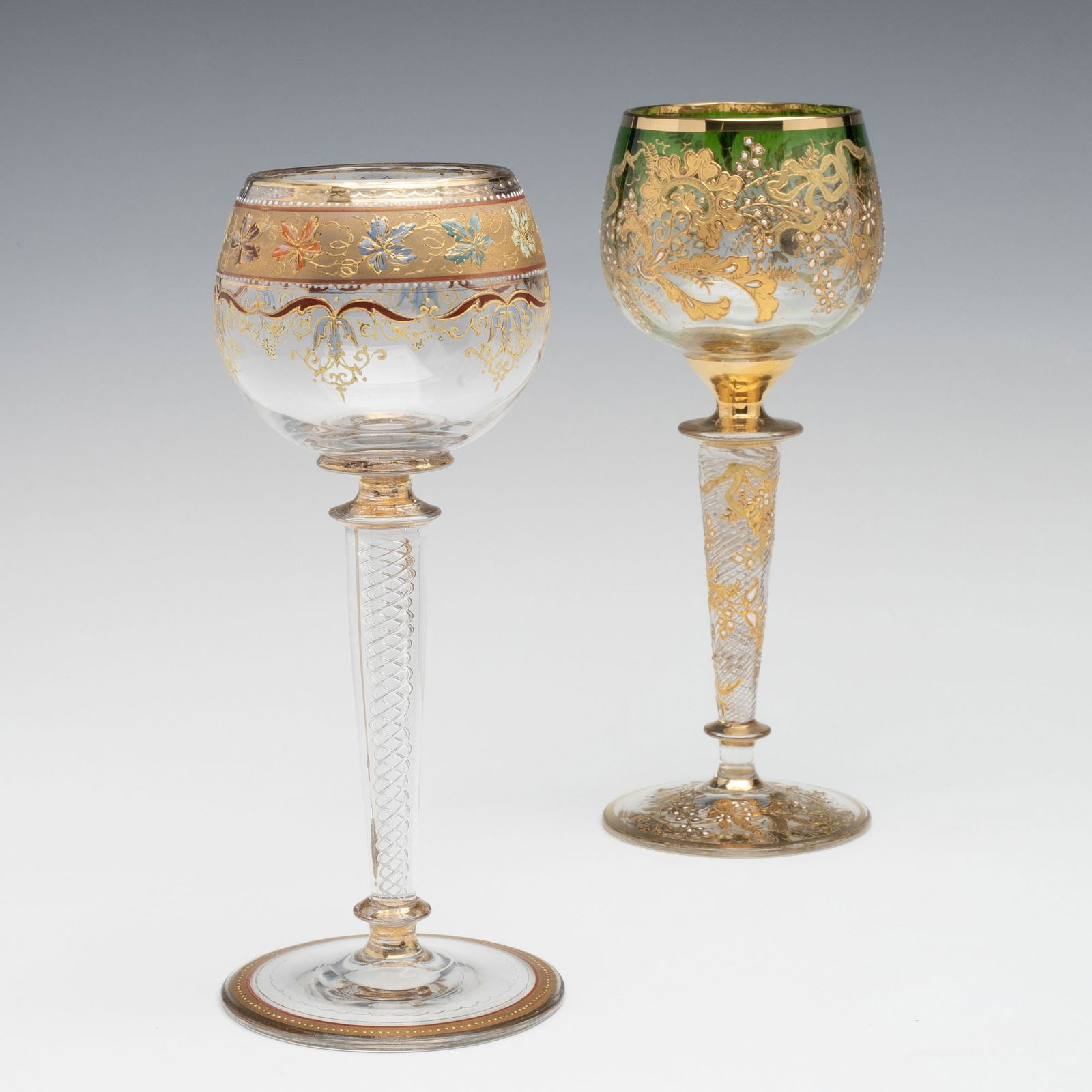 TWO FINE MOSER GLASS WINES WITH AIR TWIST STEMS: Ludwig Moser Early 20th Century The gilt and enamel glass wine goblets are embellished with rich enamels and gilding in addition to the difficult technique of an internally decorated stem. Measures 7.