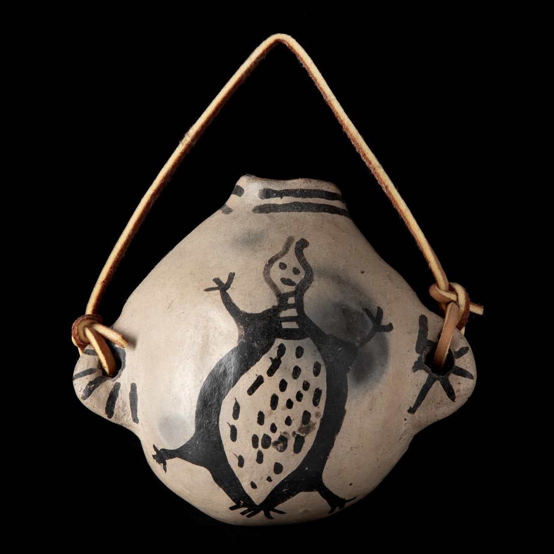 A COCHITI PUEBLO POTTERY CANTEEN WITH LIZARD: The Cochiti pottery canteen with stylized lizard in deep black on buff ground is formed and painted with the characteristics of an example of pottery made by a child in training. Measures 3 x 5 x 4.5 