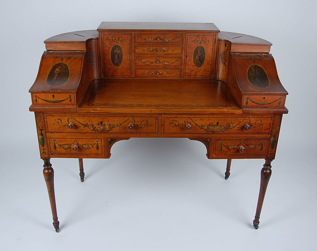EDWARDIAN PAINTED SATINWOOD CARLTON HOUSE DESK: In the Sheraton Revival style, with painted floral swags and bows, and medallions with ladies. Various swingout and hinged compartments, central drawers with doors on either side. Measures 41 x 52 x 2