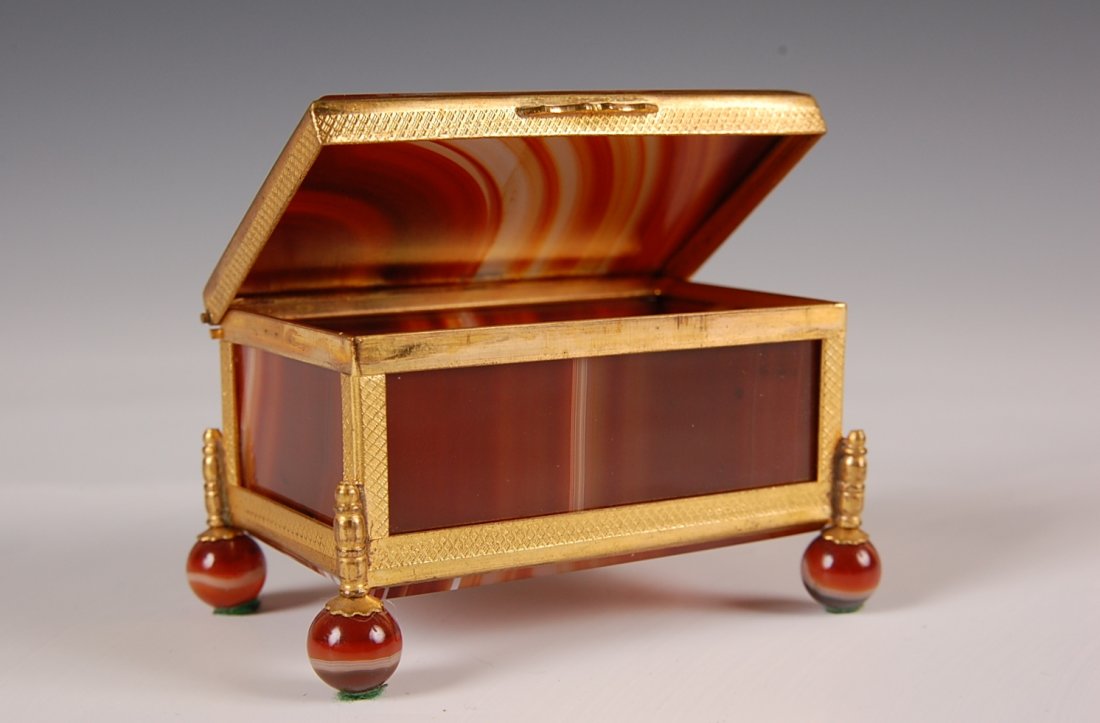 A VERY FINE BANDED AGATE AND ORMOLU HINGED LID BOX: On unique ball feet, six panels of banded agate in ormolu frame. Measures 1.75 x 3 x 2 inches.