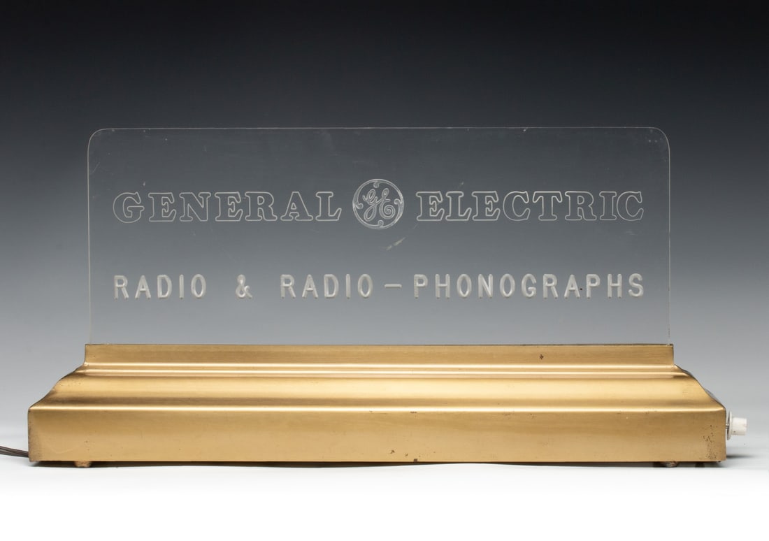 A GENERAL ELECTRIC RADIO-PHONOGRAPH ADVERTISING SIGN: The lighted marquee sign advertises radios and radio-phonograph combos circa 1960. Measures 10.75 x 21.5 inches. Without proof of exemption, be aware that internet sales tax applies to all Internet tr