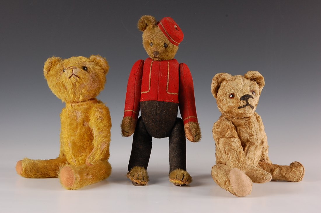 THREE ANTIQUE TEDDY BEARS: Two gold mohair bears filled with excelsior, one dressed in red coat and cap, the bellhop's head turns when the tail is twisted. Plus a short plush bear with silent growler. Each measures approximatel