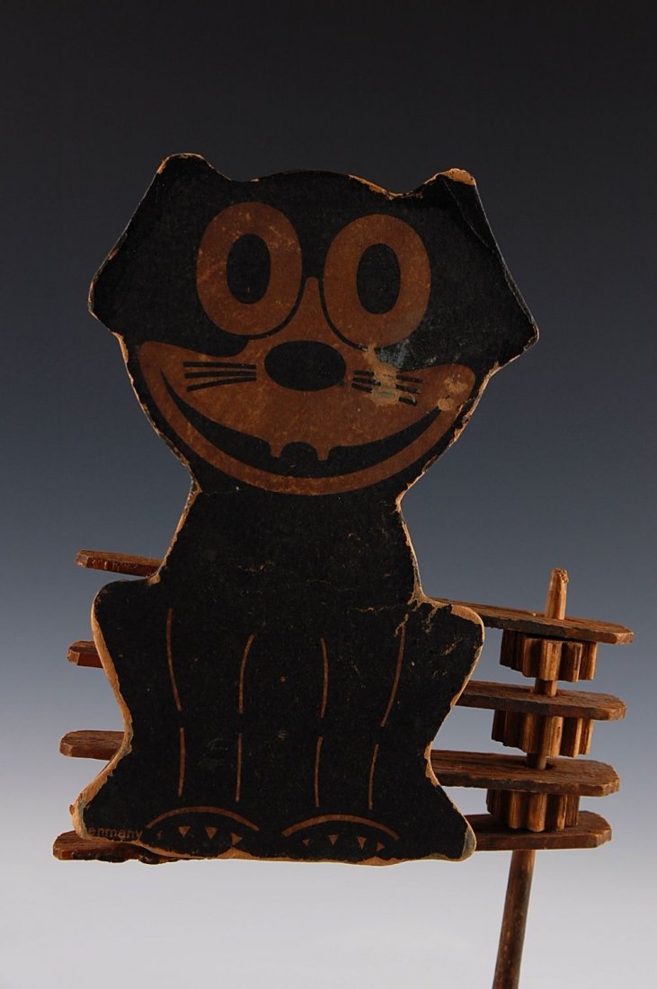 EARLY FELIX THE CAT WOOD WITH CARDBOARD NOISE MAKER: The figure measures 7 x 4 inches. It appears that the cardboard figure has been reattached to the wood noisemaker which itself is incomplete missing three flat wood strips.