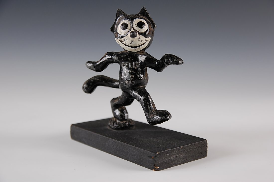 DIE CAST FELIX WALKING FIGURE MOUNTED ON WOOD: A circa 1930s figure on later wood base for display measures 4 1/2 by 3 3/4 inches