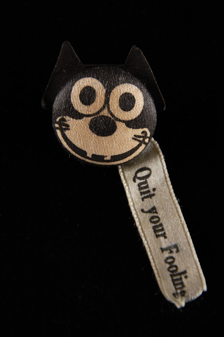FELIX THE CAT PIN BACK BUTTON, QUIT YOUR FOOLING: Cloth covered with paper years and silk ribbon. Measures 1 inch diameter.