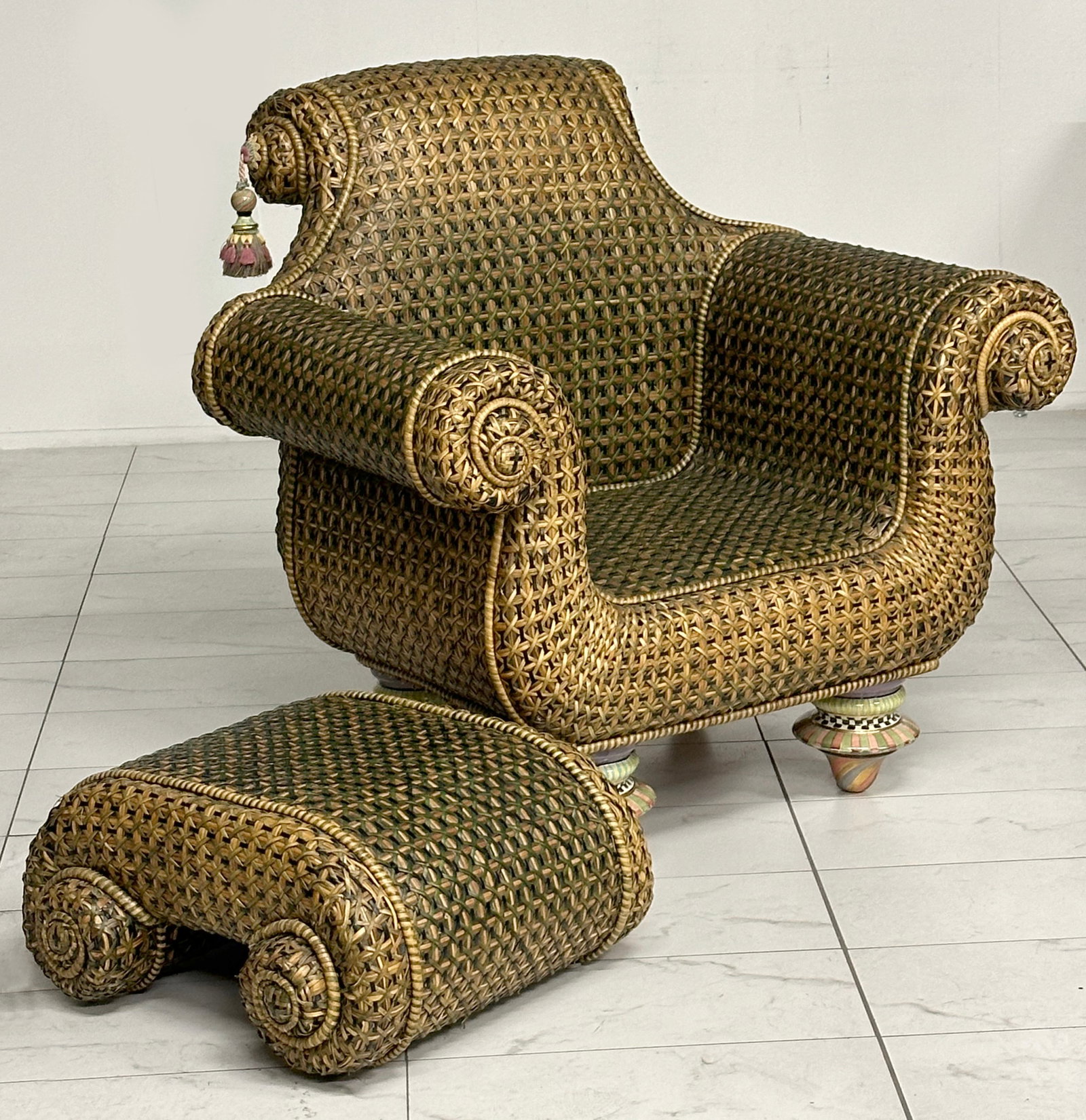 MACKENZIE CHILDS WICKER ARM CHAIR AND OTTOMAN: The large wicker chair with rolled arms and painted ceramic feet is accompanied by a matching ottoman. Please be aware that this lot is too large to ship by conventional carrier such as UPS, USPS or F