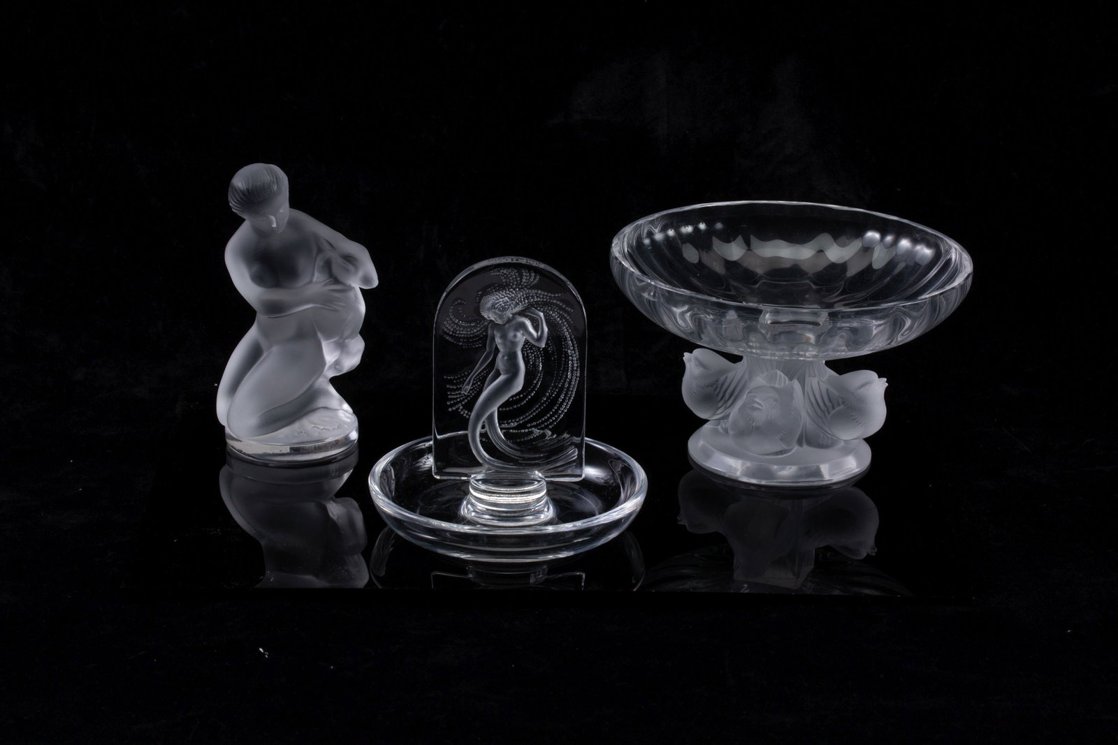 LALIQUE FRENCH CRYSTAL ARTICLES WITH NUDE MOTIF: Late 20th Century The Nogent pedestal dish with lovebirds is offered with a ring dish and frosted figure of nude females. Each is signed Lalique France underside of the base. Measures from 3.25 to 4.5