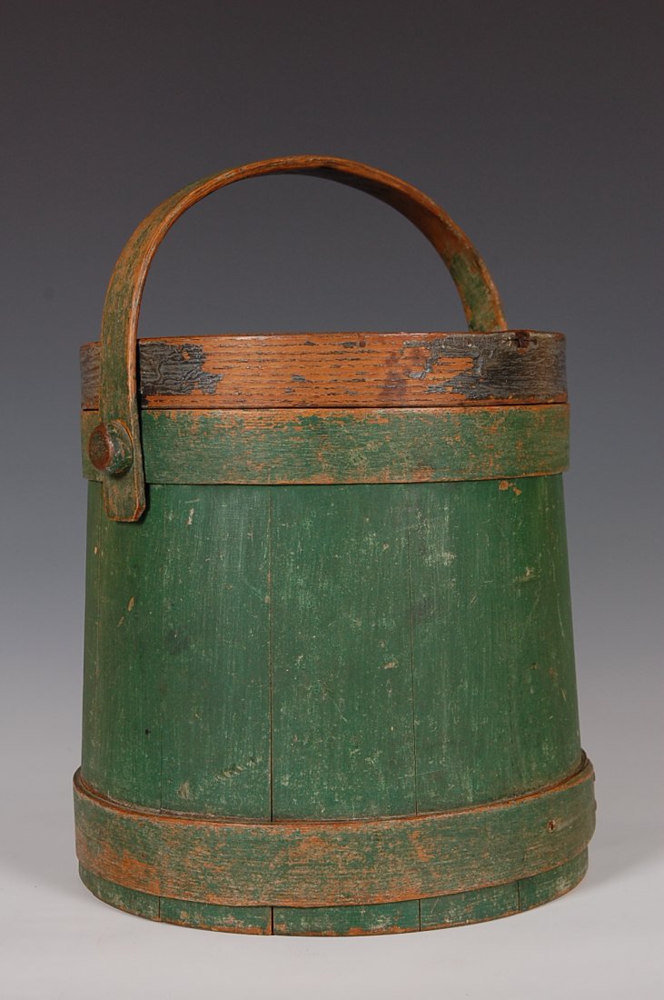 19TH C. FIRKIN IN OLD GREEN PAINT: Mushroom attached handle, pine staved sides with copper tacked oak band fingers, oak band cover with iron tacked bands. New England. Measures 10.25 x 10 inches.