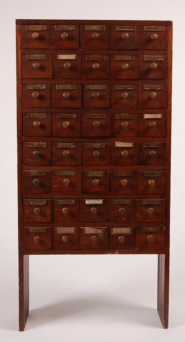 CIRCA 1900 FORTY-DRAWER APOTHECARY HARDWARE CABINET: A standing 40-drawer cabinet with old alligatored varnished surface, wood pulls and metal hardware for labels. Great standing form. Midwest. Measures 48 x 24 x 7.5 inches.